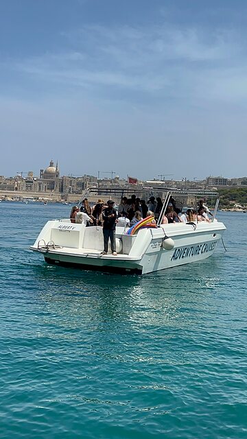 Adventure Cruises boat Albert V returning across the harbour with the Valletta skyline behind.