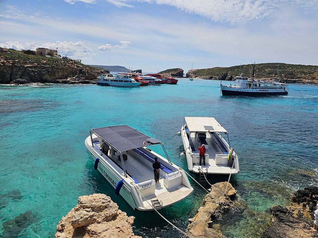 Two Adventure Cruises boats moored in the turquoise Blue Lagoon at Comino.