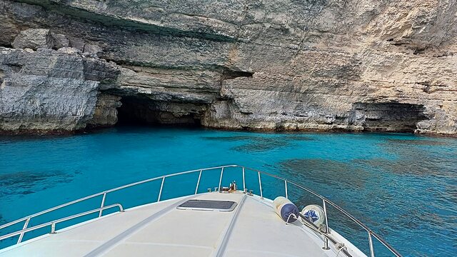 Boat bow gliding past white limestone cliffs and bright turquoise water.