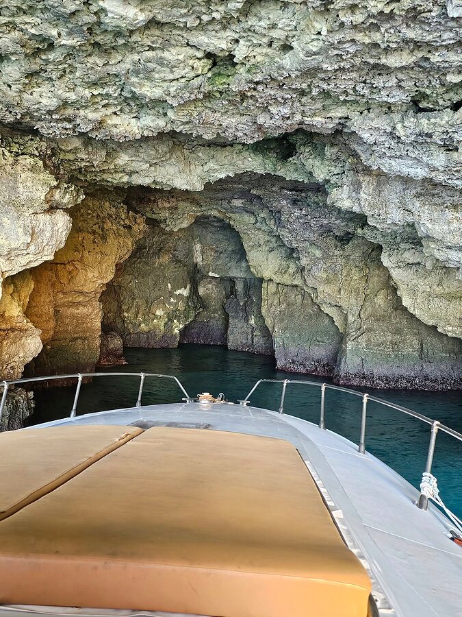 Bow of the boat entering a dark Comino sea cave.