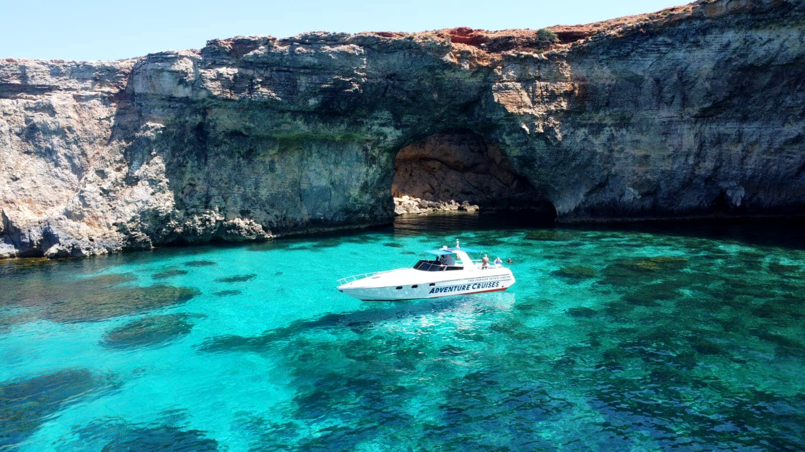Tullio Abbate cabin yacht moored beside a Comino sea cave — Adventure Cruises Malta private charter.